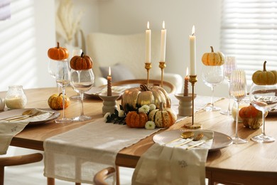 Photo of Stylish table setting with beautiful dishware, glasses and autumn decor in dining room