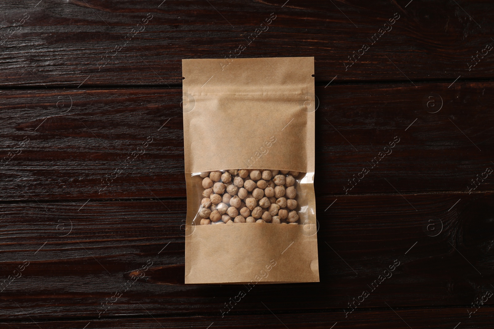 Photo of Paper pouch bag with chickpeas on wooden table, top view