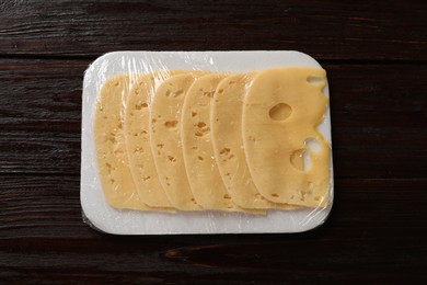 Pack of sliced cheese on wooden table, top view