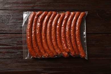 Photo of Pack of dry smoked sausages on wooden table, top view