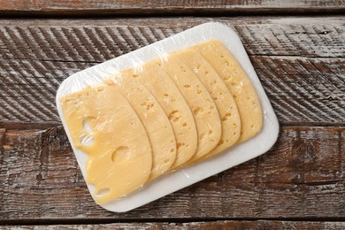 Pack of sliced cheese on wooden table, top view