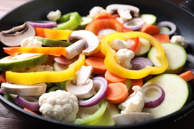 Frying pan with mix of vegetables and mushrooms on table, closeup