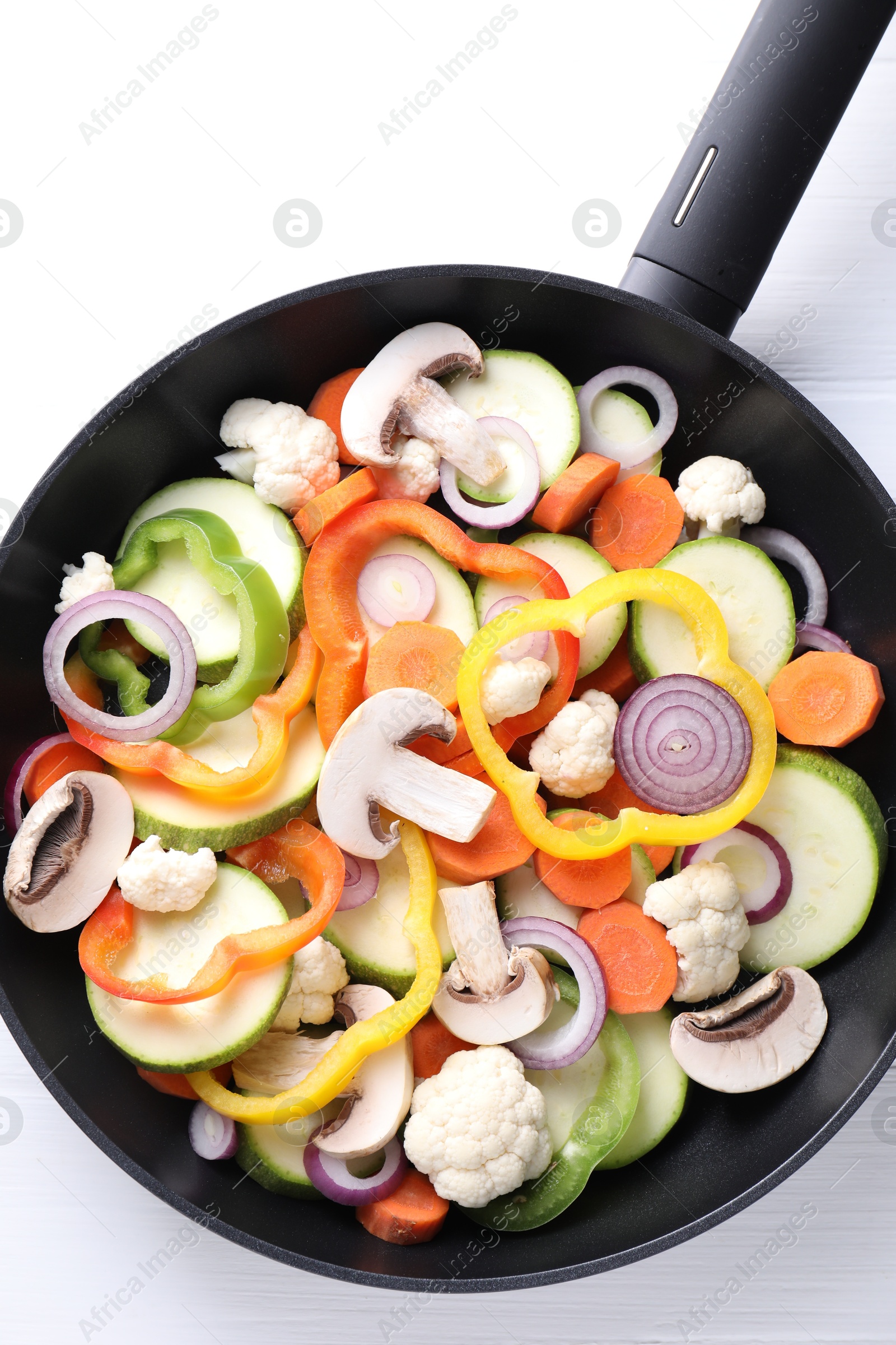 Photo of Frying pan with mix of vegetables and mushrooms on white table, top view