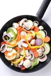 Photo of Frying pan with mix of vegetables and mushrooms on white table, top view