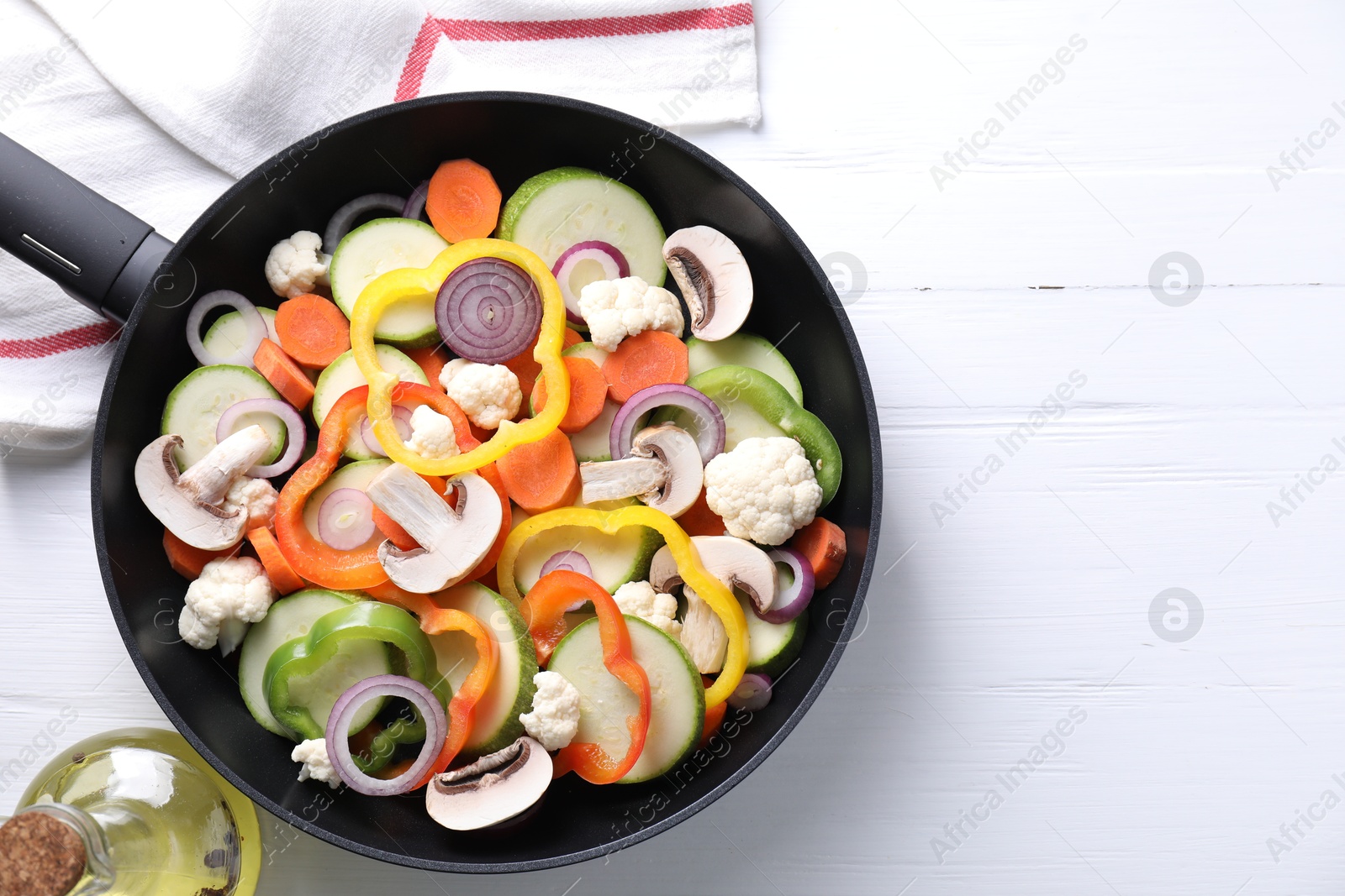 Photo of Frying pan with mix of vegetables and mushrooms on white wooden table, top view. Space for text