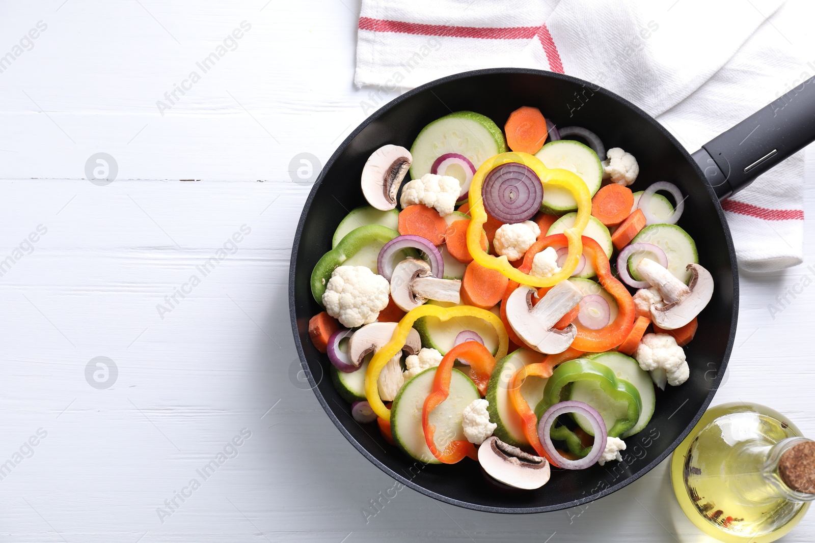 Photo of Frying pan with mix of vegetables and mushrooms on white wooden table, top view. Space for text