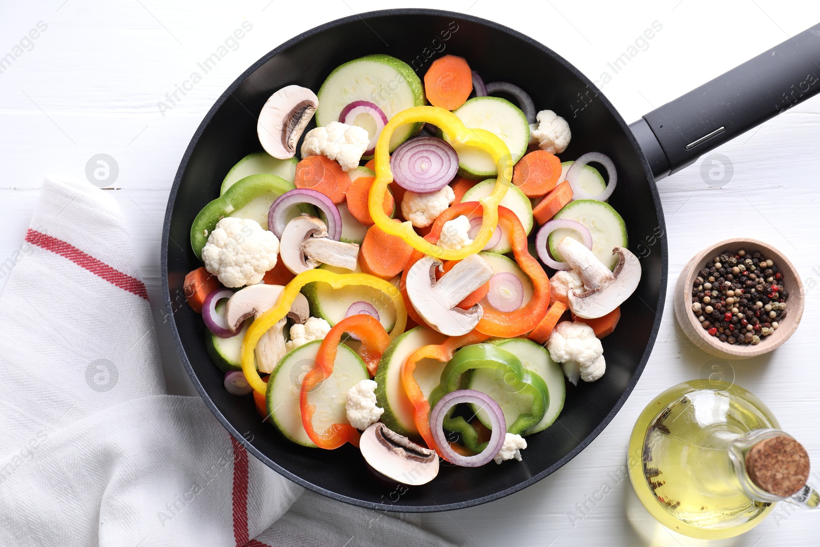 Photo of Frying pan with mix of vegetables, mushrooms and spices on white wooden table, top view