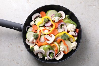 Photo of Frying pan with mix of vegetables and mushrooms on light grey table, top view