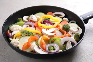 Photo of Frying pan with mix of vegetables and mushrooms on light grey table, closeup