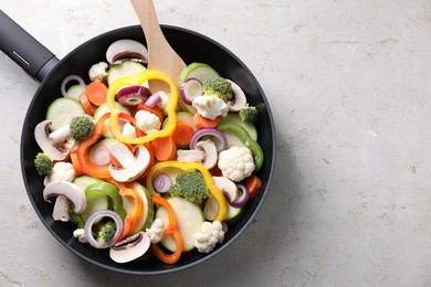 Photo of Frying pan with mix of vegetables and mushrooms on light grey table, top view. Space for text