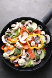 Photo of Frying pan with mix of vegetables and mushrooms on grey table, top view