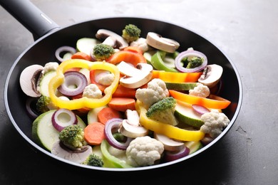 Photo of Frying pan with mix of vegetables and mushrooms on grey table, closeup