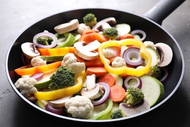 Photo of Frying pan with mix of vegetables and mushrooms on grey table, closeup