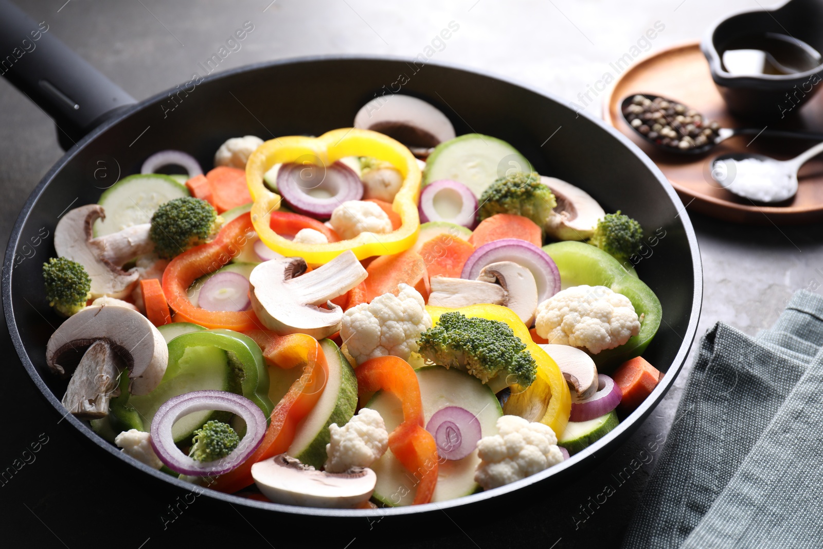 Photo of Frying pan with mix of vegetables, mushrooms and spices on table, closeup