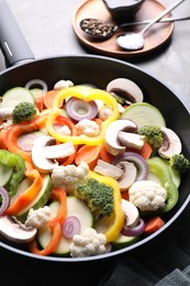 Photo of Frying pan with mix of vegetables, mushrooms and spices on table, closeup