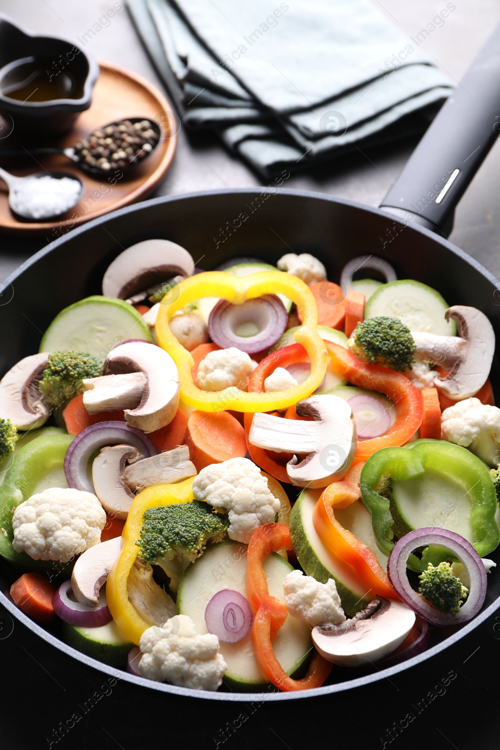 Photo of Frying pan with mix of vegetables, mushrooms and spices on table, closeup