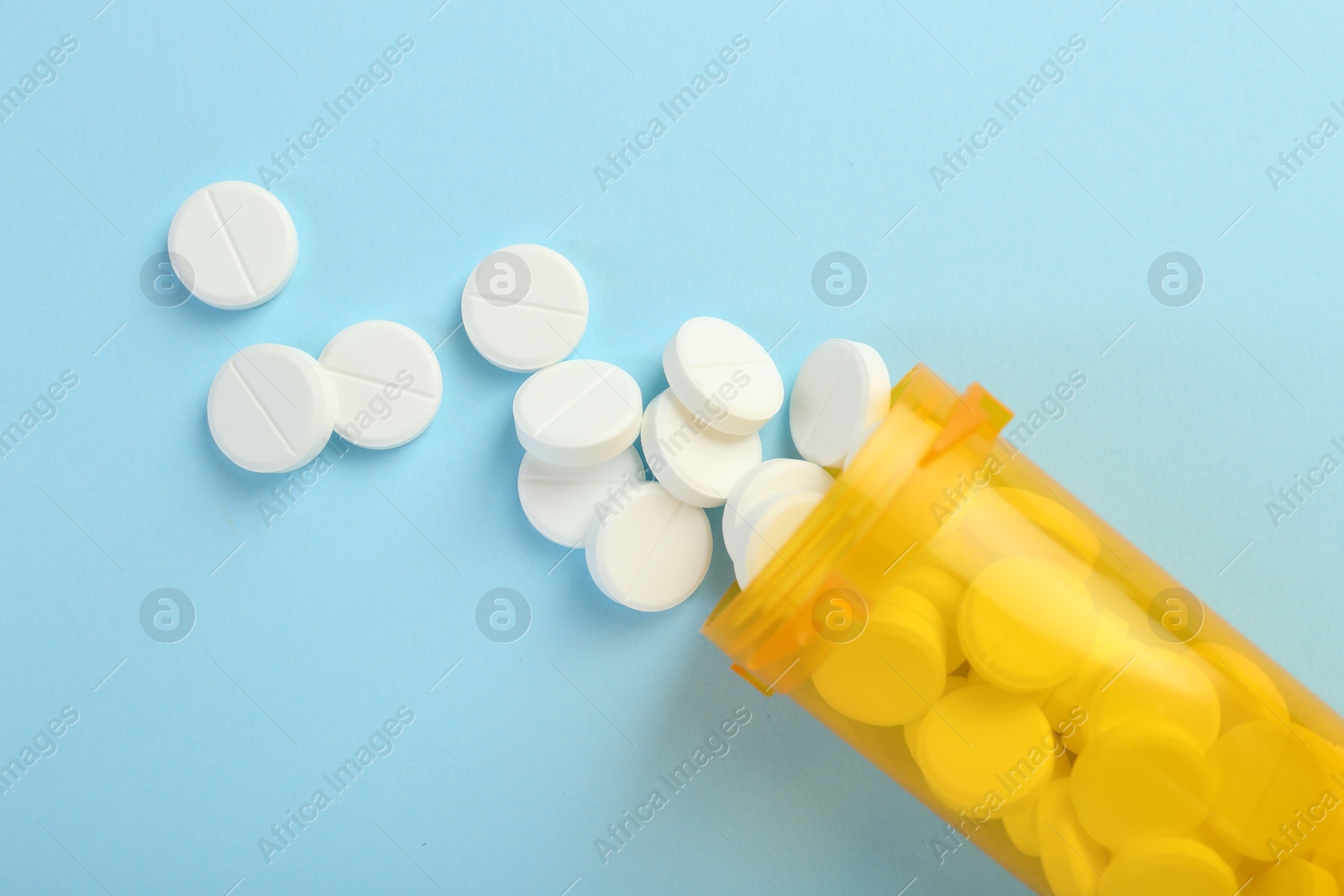 Photo of Bottle of antibiotic pills on light blue background, top view