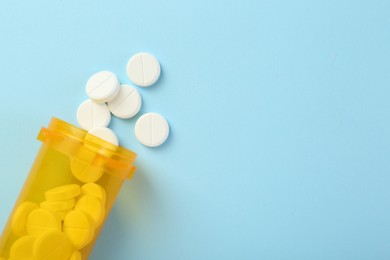 Photo of Bottle of antibiotic pills on light blue background, top view. Space for text