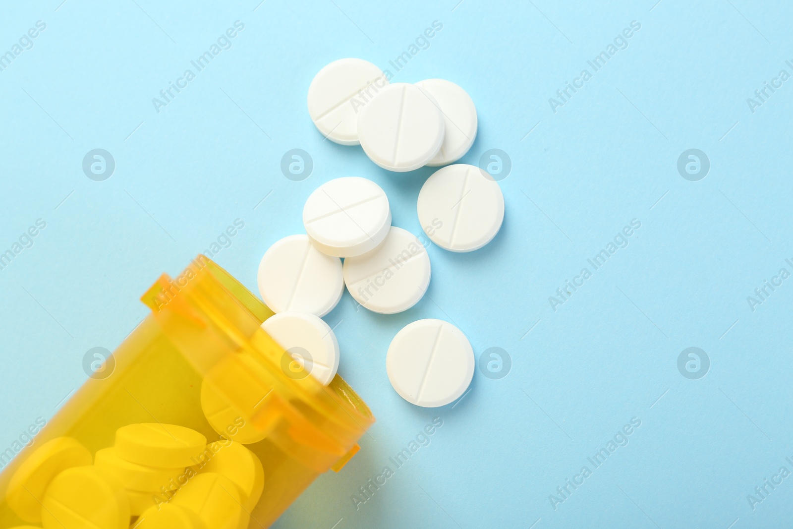 Photo of Bottle of antibiotic pills on light blue background, top view