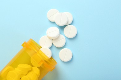 Photo of Bottle of antibiotic pills on light blue background, top view