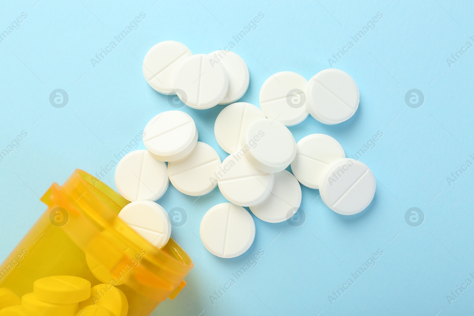 Photo of Bottle of antibiotic pills on light blue background, top view