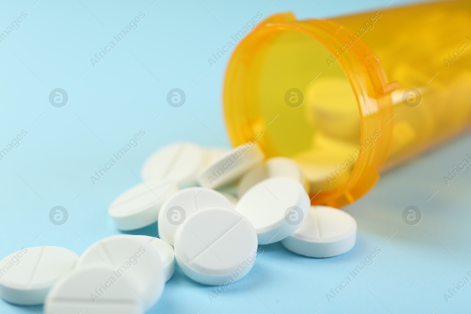 Photo of Bottle of antibiotic pills on light blue background, closeup