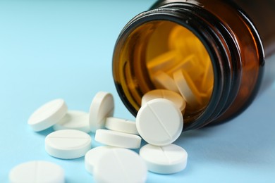 Photo of Bottle of antibiotic pills on light blue background, closeup