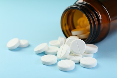 Photo of Bottle of antibiotic pills on light blue background, closeup