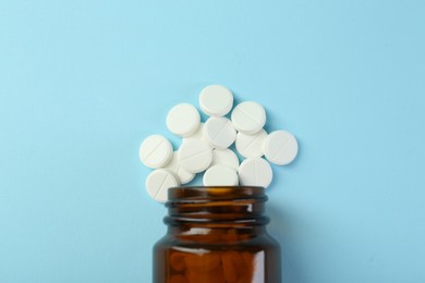 Photo of Bottle of antibiotic pills on light blue background, top view