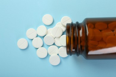 Photo of Bottle of antibiotic pills on light blue background, top view