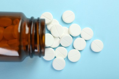 Photo of Bottle of antibiotic pills on light blue background, top view