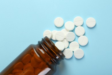 Photo of Bottle of antibiotic pills on light blue background, top view