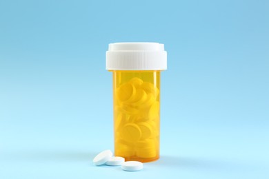 Photo of Bottle of antibiotic pills on light blue background