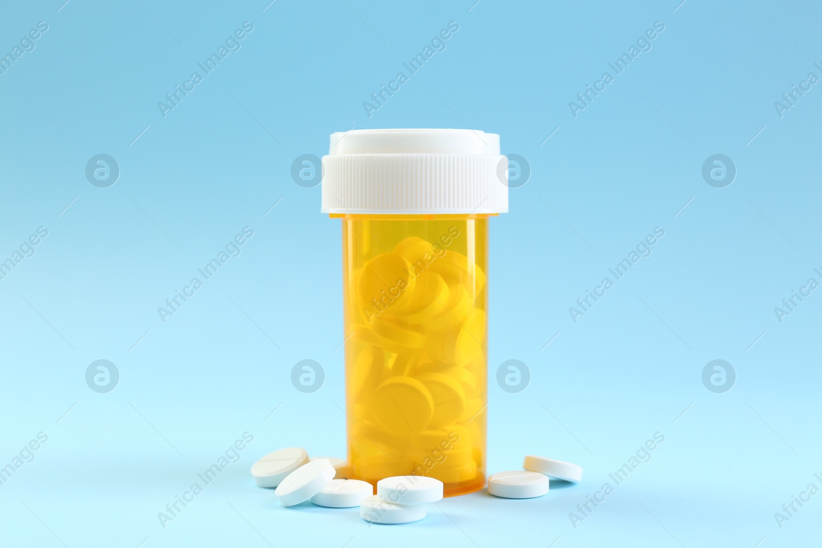 Photo of Bottle of antibiotic pills on light blue background