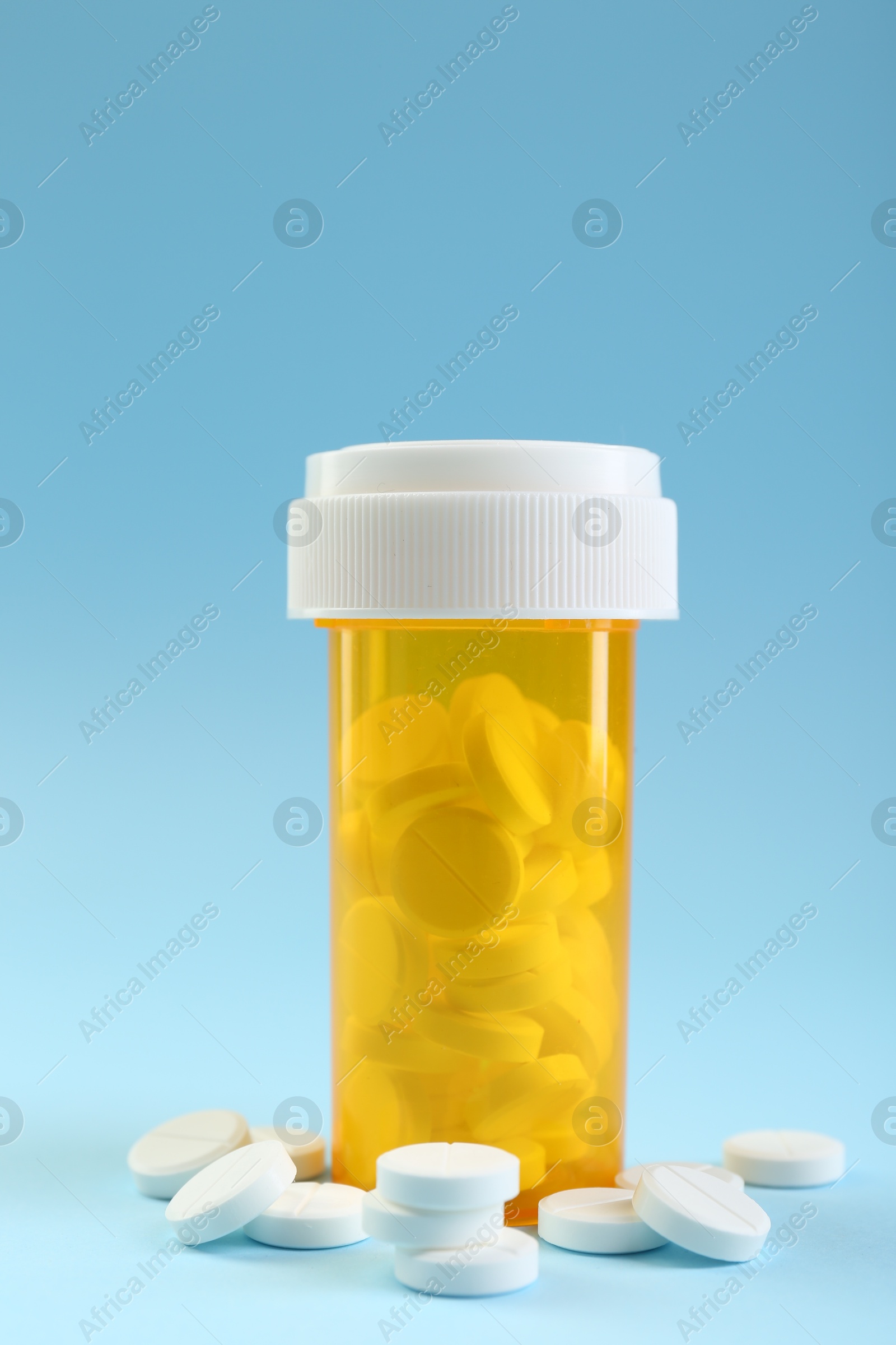 Photo of Bottle of antibiotic pills on light blue background