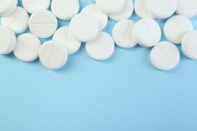 Photo of Many antibiotic pills on light blue background, top view. Space for text