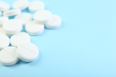 Photo of Many antibiotic pills on light blue background, closeup. Space for text