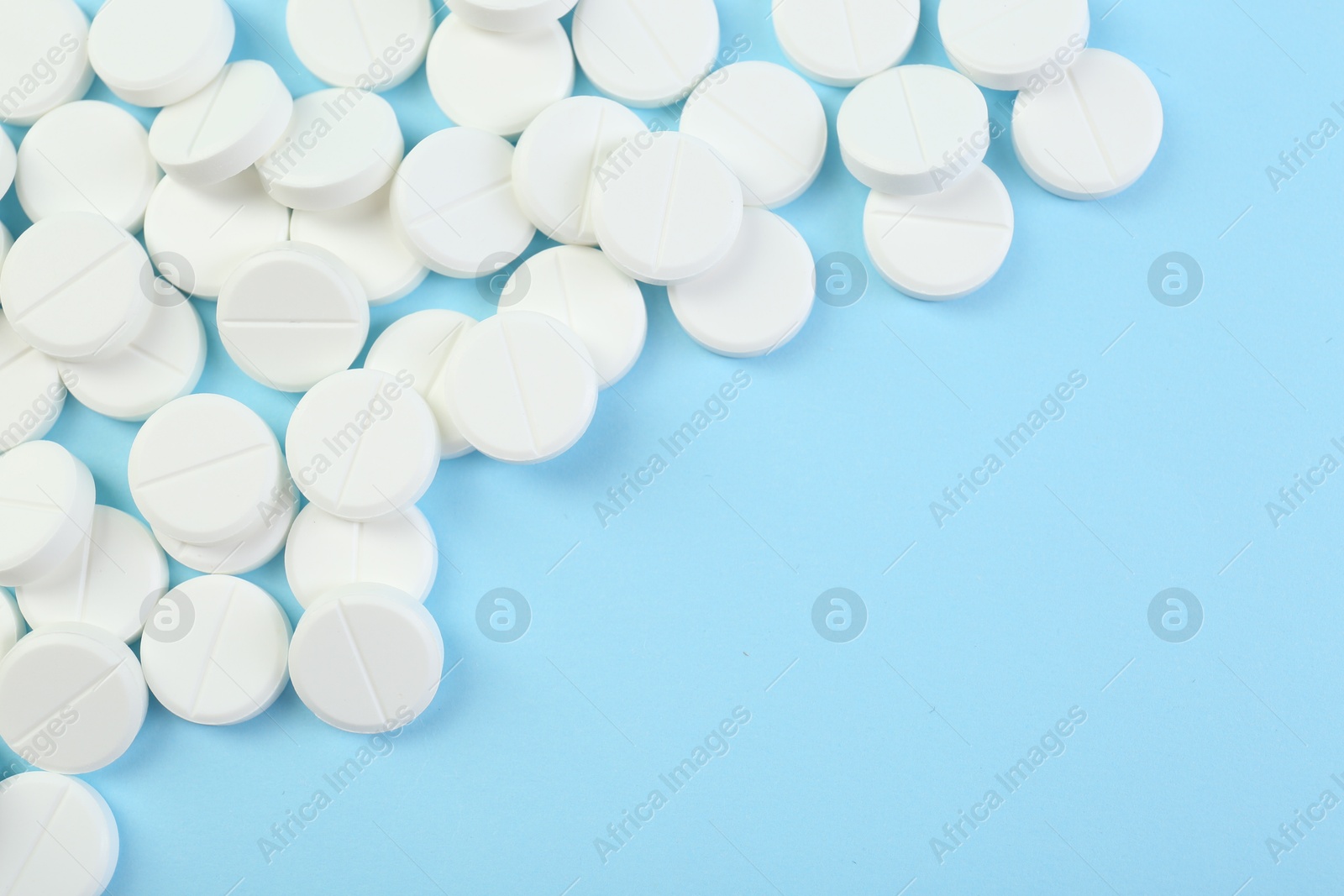 Photo of Many antibiotic pills on light blue background, top view. Space for text