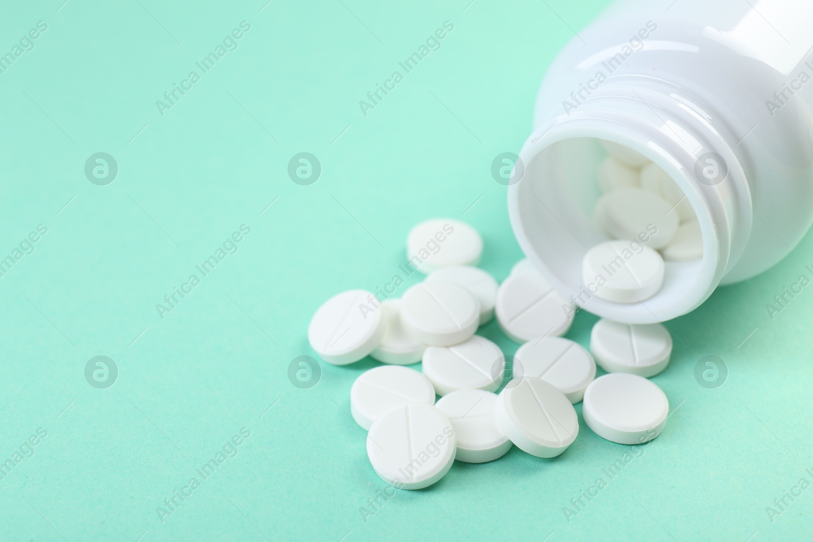 Photo of Bottle of antibiotic pills on turquoise background, closeup. Space for text