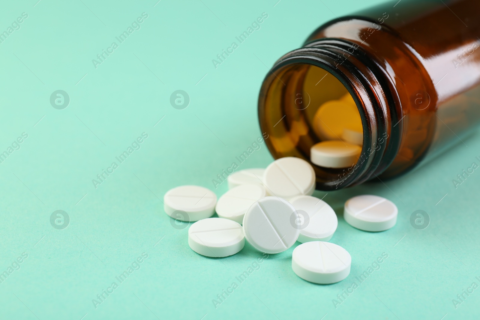 Photo of Bottle of antibiotic pills on turquoise background, closeup. Space for text