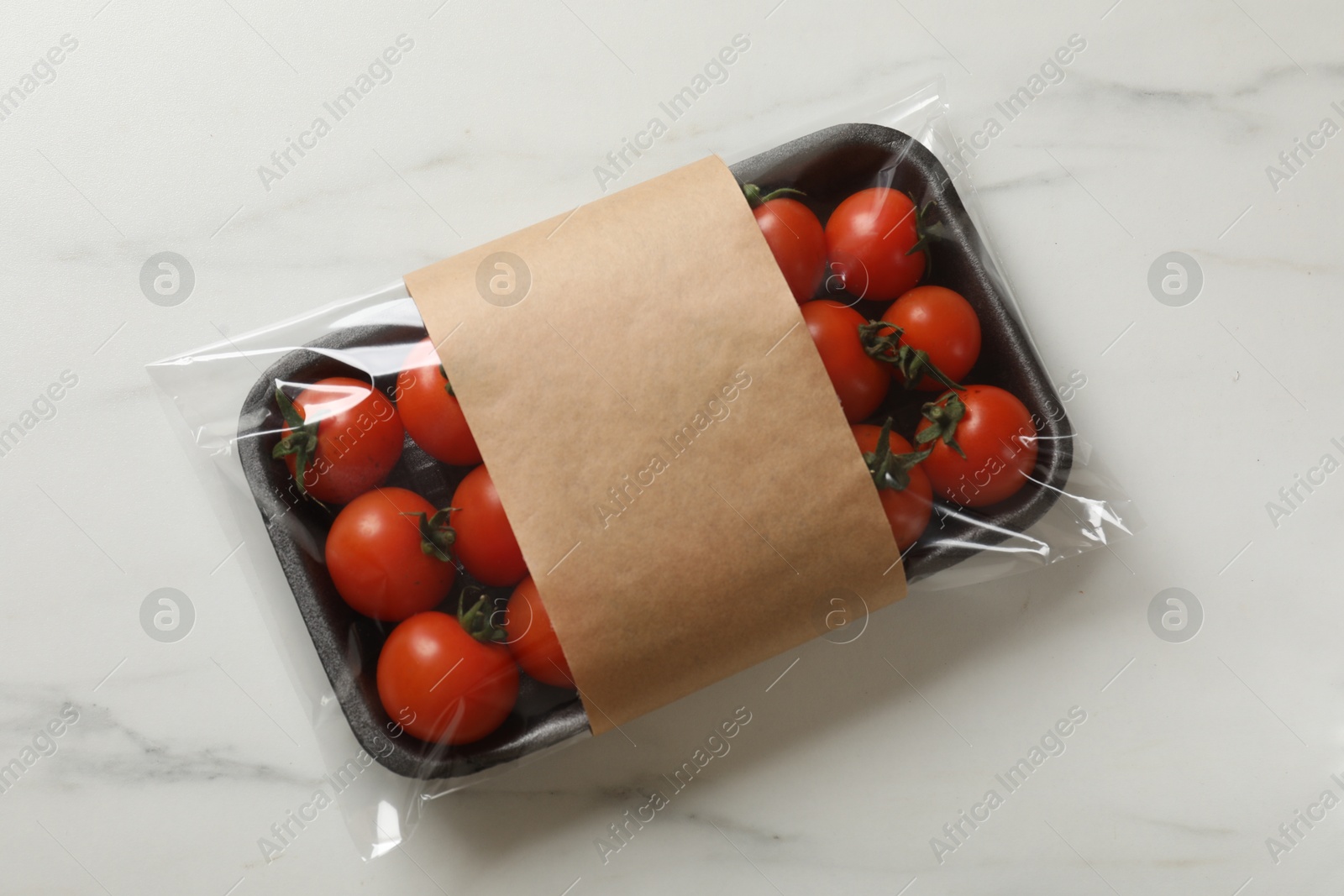 Photo of Pack of fresh tomatoes on white marble table, top view