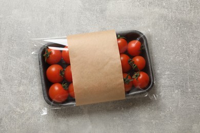 Photo of Pack of fresh tomatoes on grey table, top view