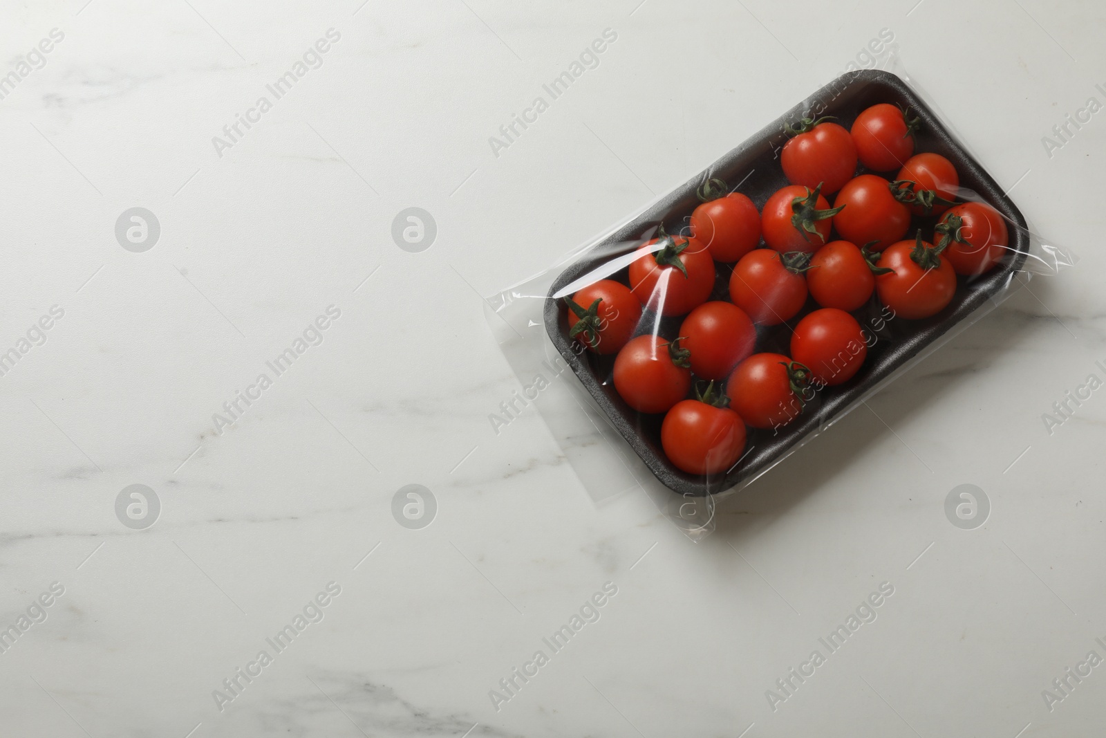 Photo of Pack of fresh tomatoes on white marble table, top view. Space for text