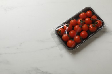 Pack of fresh tomatoes on white marble table, top view. Space for text