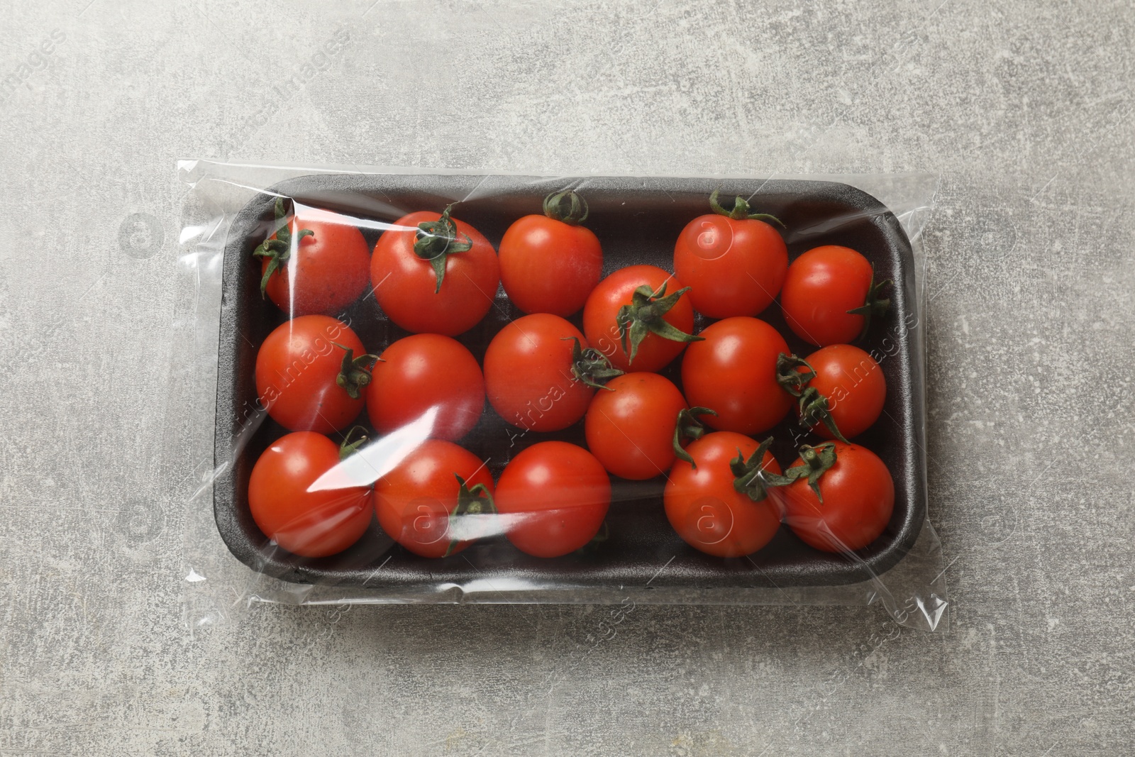 Photo of Pack of fresh tomatoes on grey table, top view