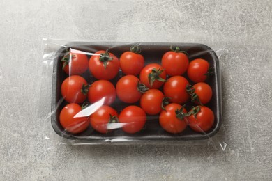 Photo of Pack of fresh tomatoes on grey table, top view