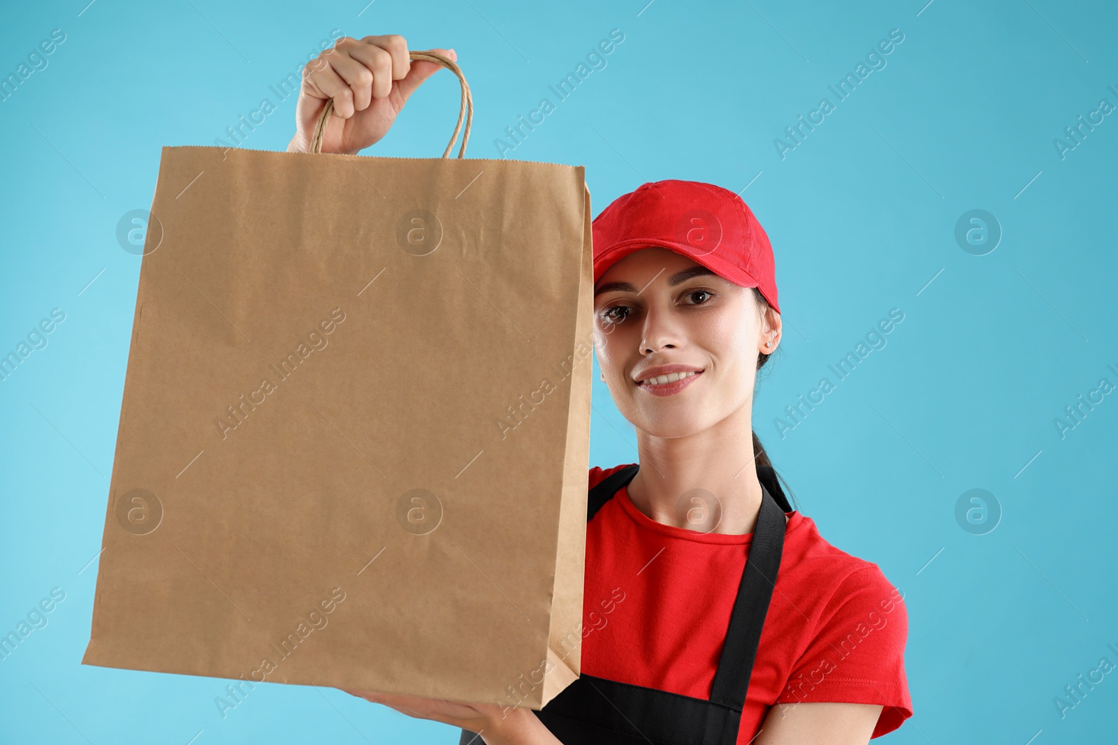 Photo of Fast-food worker with paper bag on light blue background