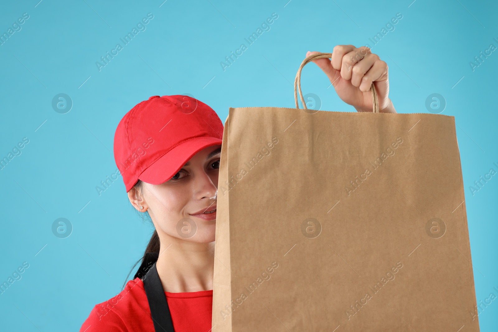 Photo of Fast-food worker with paper bag on light blue background