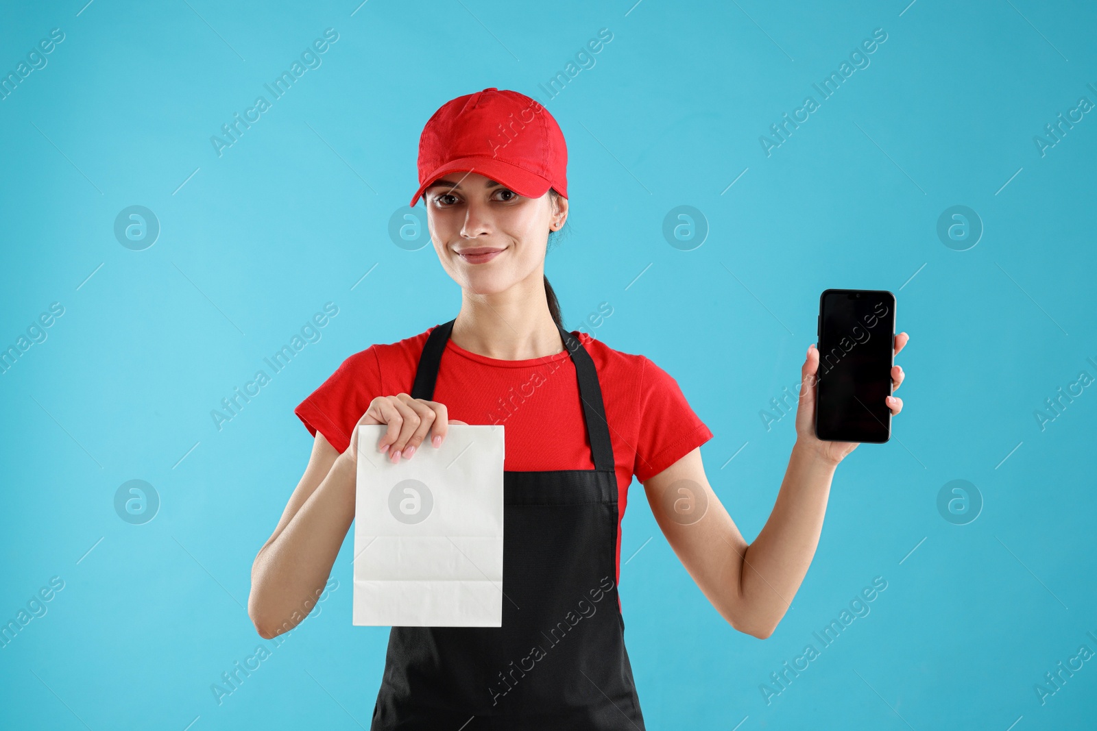 Photo of Fast-food worker with paper bag and smartphone on light blue background