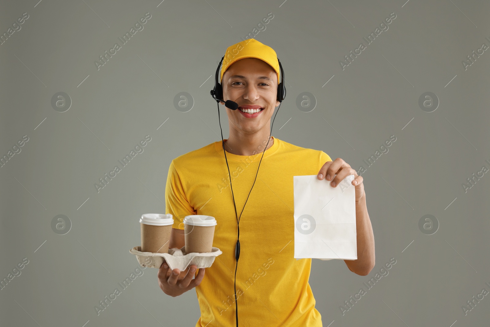 Photo of Fast-food worker with paper bag and cups on gray background